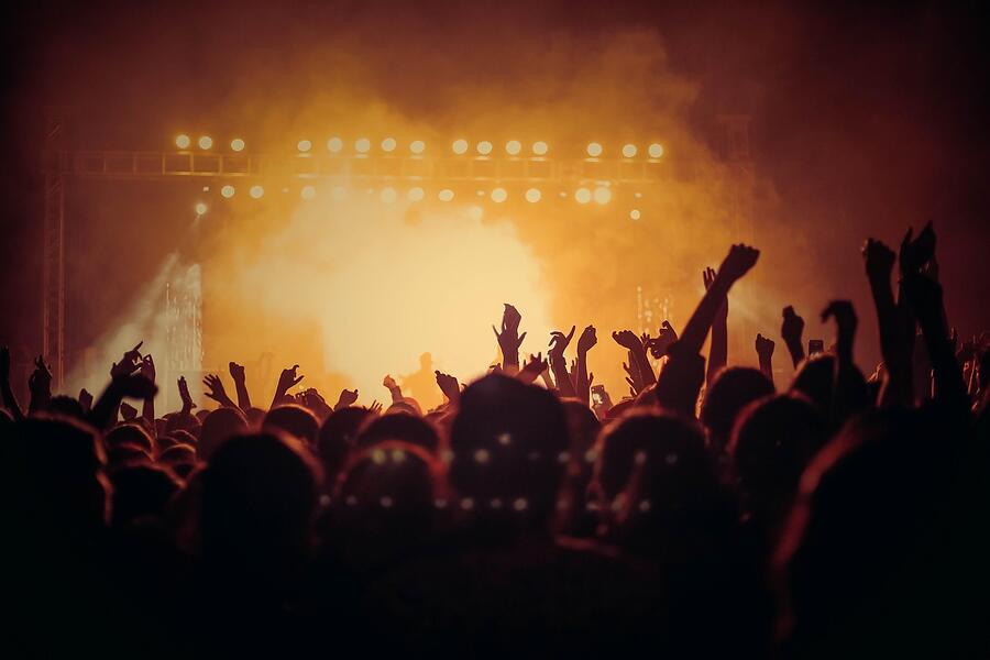 Raised hands in a crowd close to a stage
